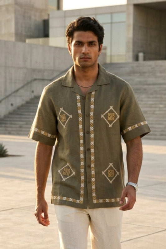Man wearing a patterned shirt standing outdoors with a building in the background