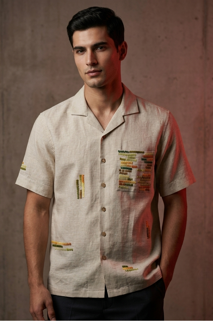 Man wearing a beige shirt with colorful patches against a brown background