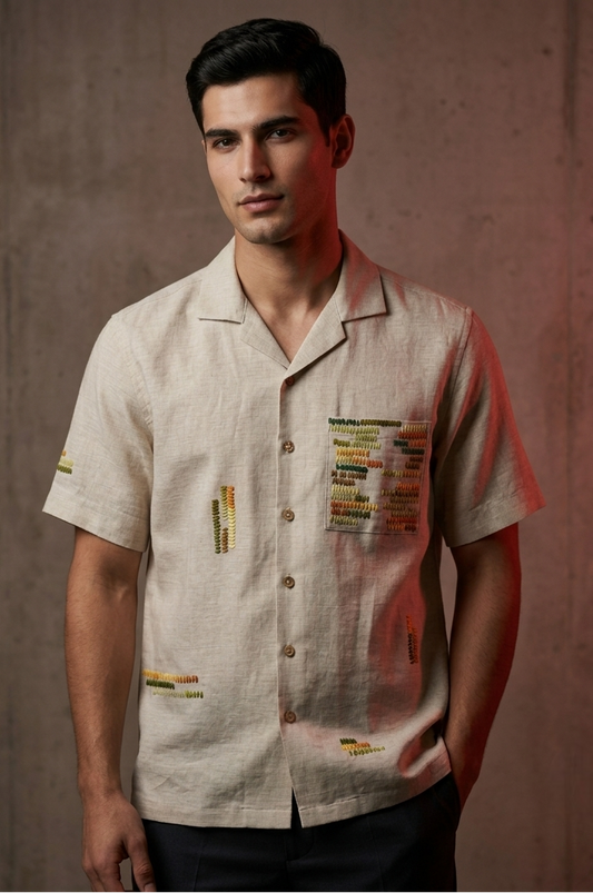 Man wearing a beige shirt with colorful patches against a brown background