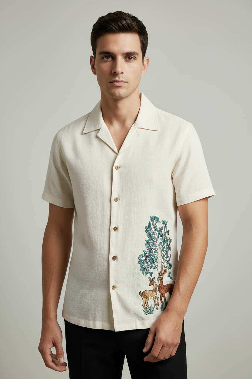 Embroidered design of two deer under a tree on a white shirt.