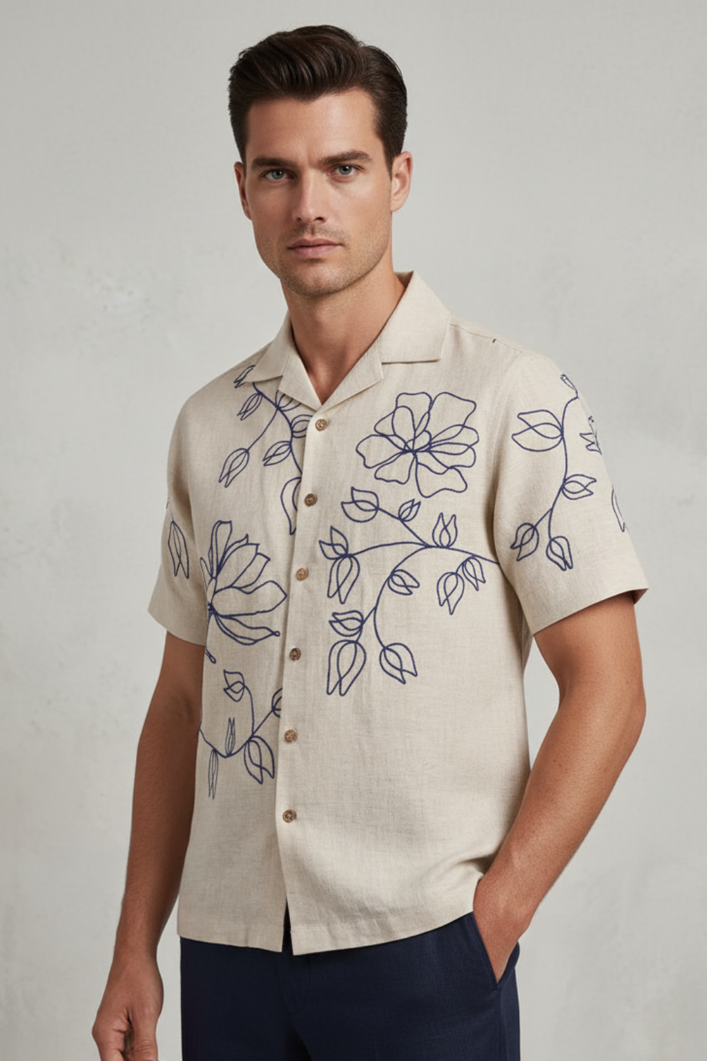 Man wearing a beige shirt with floral embroidery on a plain background