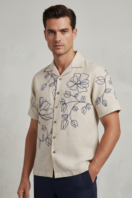 Man wearing a beige shirt with floral embroidery on a plain background
